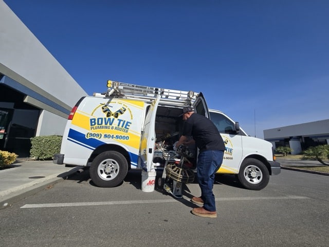 Bow Tie plumber taking equipment out of his van on the way to a hard water quality call.