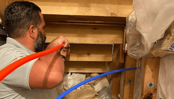 Bow Tie technician repiping a home with pipes in his hands.