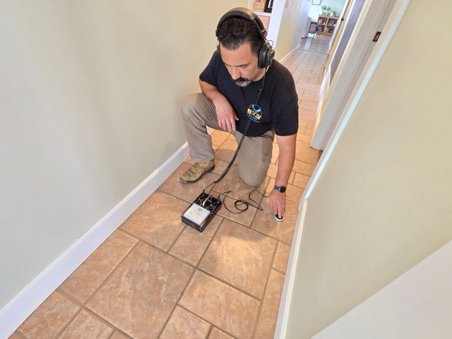 Bow Tie technician using an electronic leak detector in a home.