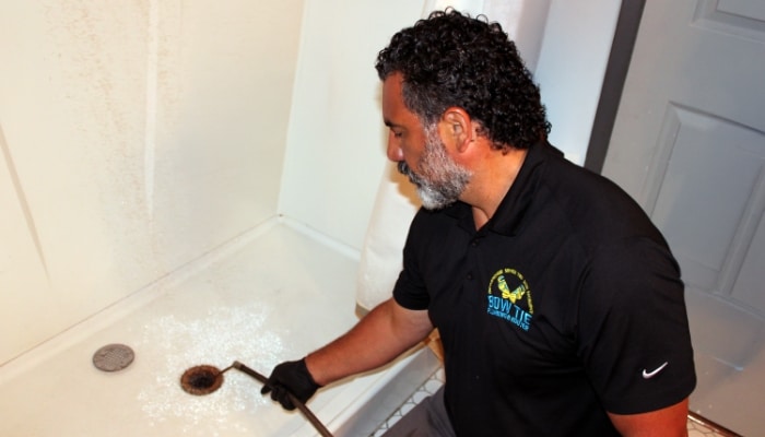 Bow Tie Plumber Clearing Shower Drain