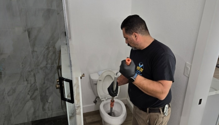 Plumber Unclogging Toilet
